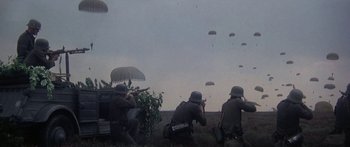 Movie still from “A Bridge Too Far” (1977), directed by Richard Attenborough – A group of men in military uniforms are flying parachutists in the sky; Wide shot, High angle