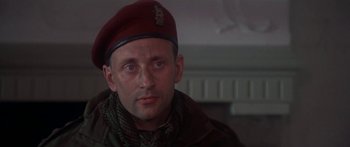 Movie still from “A Bridge Too Far” (1977), directed by Richard Attenborough – A man wearing a red hat and a scarf; Close Up shot, Low angle