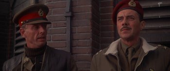 Movie still from “A Bridge Too Far” (1977), directed by Richard Attenborough – Two men standing next to each other in front of a brick wall; Close Up shot, Low angle