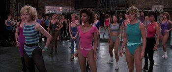 Movie still from “A Chorus Line” (1985), directed by Richard Attenborough – A group of women are standing in a dance studio; Medium shot, Over the shoulder angle
