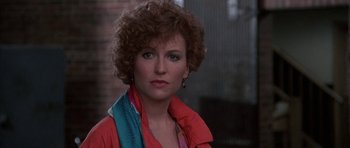 Movie still from “A Chorus Line” (1985), directed by Richard Attenborough – A person with curly hair wearing a red jacket; Close Up shot, Over the shoulder angle