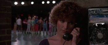 Movie still from “A Chorus Line” (1985), directed by Richard Attenborough – A woman with curly hair talking on a phone; Close Up shot, Low angle