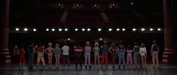Movie still from “A Chorus Line” (1985), directed by Richard Attenborough – A group of people standing in front of an audience; Wide shot, Low angle