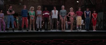 Movie still from “A Chorus Line” (1985), directed by Richard Attenborough – A group of people standing on a stage wearing bathing suits; Wide shot, Low angle