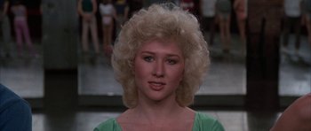 Movie still from “A Chorus Line” (1985), directed by Richard Attenborough – A woman with blonde curly hair wearing a green shirt; Close Up shot, Low angle