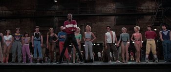 Movie still from “A Chorus Line” (1985), directed by Richard Attenborough – A group of people standing on a stage; Wide shot, Low angle