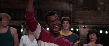 Movie still from “A Chorus Line” (1985), directed by Richard Attenborough – A young man with his mouth wide open is holding his hands up; Close Up shot, Low angle