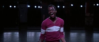 Movie still from “A Chorus Line” (1985), directed by Richard Attenborough – A young man laughing while standing on a stage; Medium shot, Low angle