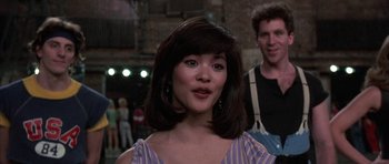 Movie still from “A Chorus Line” (1985), directed by Richard Attenborough – A woman with a short hair cut and bangs standing in front of a man; Medium shot, Over the shoulder angle