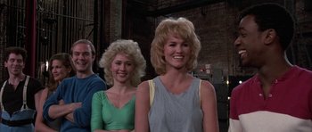 Movie still from “A Chorus Line” (1985), directed by Richard Attenborough – Two women and a man are posing for a picture; Medium shot, Low angle