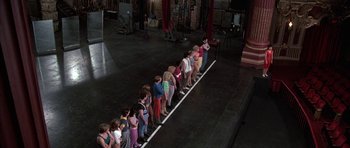 Movie still from “A Chorus Line” (1985), directed by Richard Attenborough – A group of people standing in a line on a stage; Wide shot, High angle