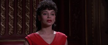 Movie still from “A Chorus Line” (1985), directed by Richard Attenborough – A woman in a red dress is standing in front of a wall; Close Up shot, Low angle