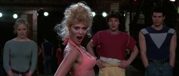 Movie still from “A Chorus Line” (1985), directed by Richard Attenborough – A woman in a pink top and a man in a red shirt; Medium shot, Low angle