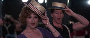 Movie still from “A Chorus Line” (1985), directed by Richard Attenborough – A woman with a hat on her head and a man with a hat on her head; Close Up shot, Over the shoulder angle