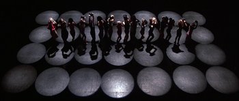Movie still from “A Chorus Line” (1985), directed by Richard Attenborough – A group of people standing in a room with lights on the floor; Extreme Wide shot, Overhead angle