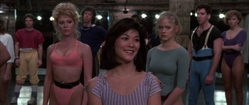 Movie still from “A Chorus Line” (1985), directed by Richard Attenborough – A group of people standing in front of a brick wall; Medium shot, Over the shoulder angle