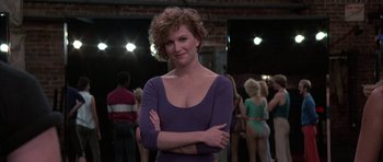 Movie still from “A Chorus Line” (1985), directed by Richard Attenborough – A woman standing in front of a group of people; Medium shot, Over the shoulder angle