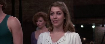 Movie still from “A Chorus Line” (1985), directed by Richard Attenborough – A woman standing next to another woman in front of a building; Close Up shot, Over the shoulder angle