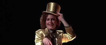 Movie still from “A Chorus Line” (1985), directed by Richard Attenborough – A woman wearing a gold top hat with polka dots on it; Close Up shot, Low angle