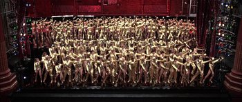 Movie still from “A Chorus Line” (1985), directed by Richard Attenborough – A large group of people standing next to each other on a stage; Extreme Wide shot, High angle