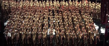 Movie still from “A Chorus Line” (1985), directed by Richard Attenborough – A large group of people in uniform are sitting in rows; Extreme Wide shot, High angle