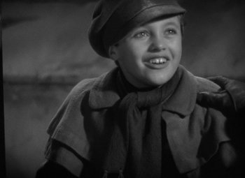 Movie still from “A Christmas Carol” (1938), directed by Edwin L. Marin – A black and white photo of a young boy wearing a hat; Close Up shot, High angle