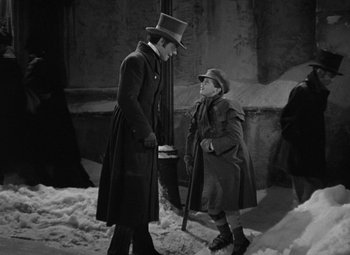 Movie still from “A Christmas Carol” (1938), directed by Edwin L. Marin – A man in a top hat talking to another man in a coat and hat; Medium shot, High angle