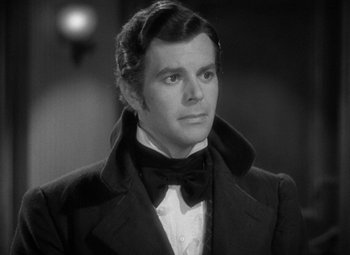 Movie still from “A Christmas Carol” (1938), directed by Edwin L. Marin – A black and white photo of a man wearing a suit and bow tie; Close Up shot, Over the shoulder angle