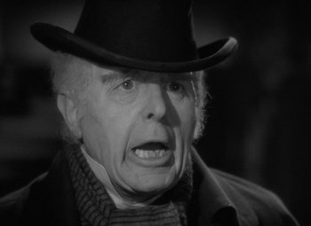 Movie still from “A Christmas Carol” (1938), directed by Edwin L. Marin – An old man wearing a black hat and a scarf; Close Up shot, Over the shoulder angle