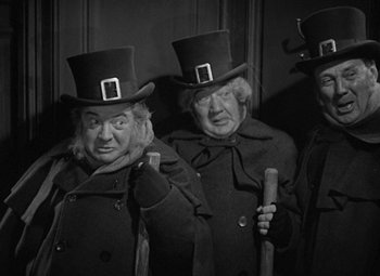 Movie still from “A Christmas Carol” (1938), directed by Edwin L. Marin – A group of people wearing top hats and holding a cane; Medium shot, High angle