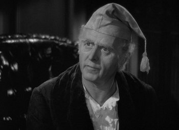 Movie still from “A Christmas Carol” (1938), directed by Edwin L. Marin – An older man wearing a hat and a jacket; Close Up shot, Over the shoulder angle