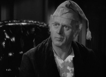 Movie still from “A Christmas Carol” (1938), directed by Edwin L. Marin – An older man wearing a santa claus hat; Close Up shot, Over the shoulder angle