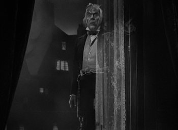 Movie still from “A Christmas Carol” (1938), directed by Edwin L. Marin – A black and white photo of a man in a suit and tie; Medium shot, Low angle