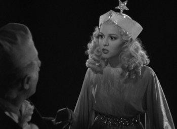 Movie still from “A Christmas Carol” (1938), directed by Edwin L. Marin – A black and white photo of a woman wearing a crown; Medium shot, Over the shoulder angle
