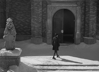 Movie still from “A Christmas Carol” (1938), directed by Edwin L. Marin – A person walking in the snow near a building; Wide shot, Low angle