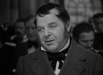 Movie still from “A Christmas Carol” (1938), directed by Edwin L. Marin – An old photo of a man in a suit and bow tie; Close Up shot, Over the shoulder angle