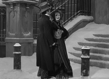 Movie still from “A Christmas Carol” (1938), directed by Edwin L. Marin – A man and a woman dressed in victorian clothing; Wide shot, High angle