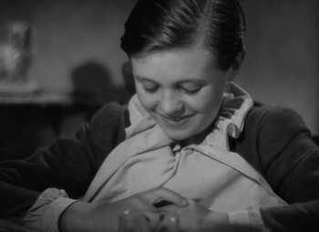 Movie still from “A Christmas Carol” (1938), directed by Edwin L. Marin – A young woman is smiling while holding a cell phone; Close Up shot, High angle