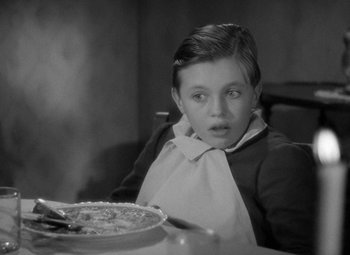 Movie still from “A Christmas Carol” (1938), directed by Edwin L. Marin – A boy sitting at a table with a plate of food; Medium shot, High angle