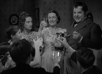 Movie still from “A Christmas Carol” (1938), directed by Edwin L. Marin – A black and white photo of people toasting with wine glasses; Medium shot, Low angle