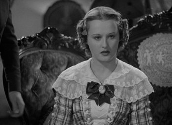 Movie still from “A Christmas Carol” (1938), directed by Edwin L. Marin – A woman in a plaid dress sitting in a chair; Close Up shot, High angle