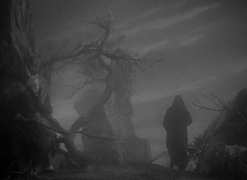 Movie still from “A Christmas Carol” (1938), directed by Edwin L. Marin – A person standing next to a dead tree in the fog; Wide shot, Low angle