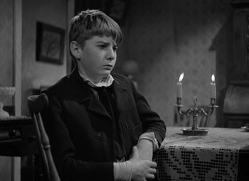 Movie still from “A Christmas Carol” (1938), directed by Edwin L. Marin – A young boy sitting at a table in front of candles; Medium shot, High angle