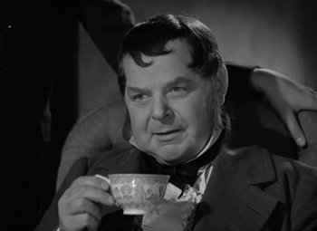 Movie still from “A Christmas Carol” (1938), directed by Edwin L. Marin – A man in a suit holding a cup of tea; Close Up shot, Over the shoulder angle