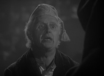 Movie still from “A Christmas Carol” (1938), directed by Edwin L. Marin – An old man wearing a hat and looking angry; Close Up shot, Over the shoulder angle