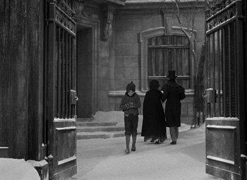 Movie still from “A Christmas Carol” (1938), directed by Edwin L. Marin – A black and white photo of a group of people walking down a street; Wide shot, High angle