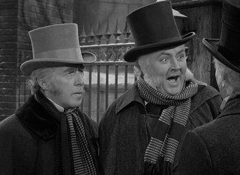 Movie still from “A Christmas Carol” (1938), directed by Edwin L. Marin – Two men wearing hats and scarves standing next to each other; Close Up shot, Over the shoulder angle