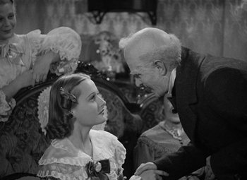 Movie still from “A Christmas Carol” (1938), directed by Edwin L. Marin – An older man and a young girl are talking to each other; Medium shot, Over the shoulder angle