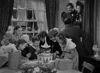 Movie still from “A Christmas Carol” (1938), directed by Edwin L. Marin – A group of people gathered around a birthday cake; Medium shot, High angle