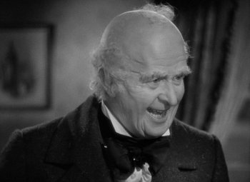 Movie still from “A Christmas Carol” (1938), directed by Edwin L. Marin – An old man with a bald head wearing a suit and tie; Close Up shot, High angle